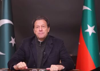 رئيس الوزراء الباكستاني السابق عمران خان يجلس بين علم باكستان وعلم حزب حركة الإنصاف